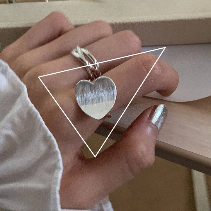 Silberner Herzring an Hand, modisches Accessoire, elegantes Schmuckdesign, Damenmode.