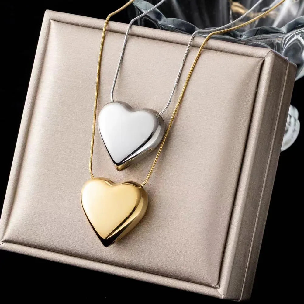 Zwei herzförmige Anhänger, gold und silber, auf Geschenkbox, eleganter Schmuck.