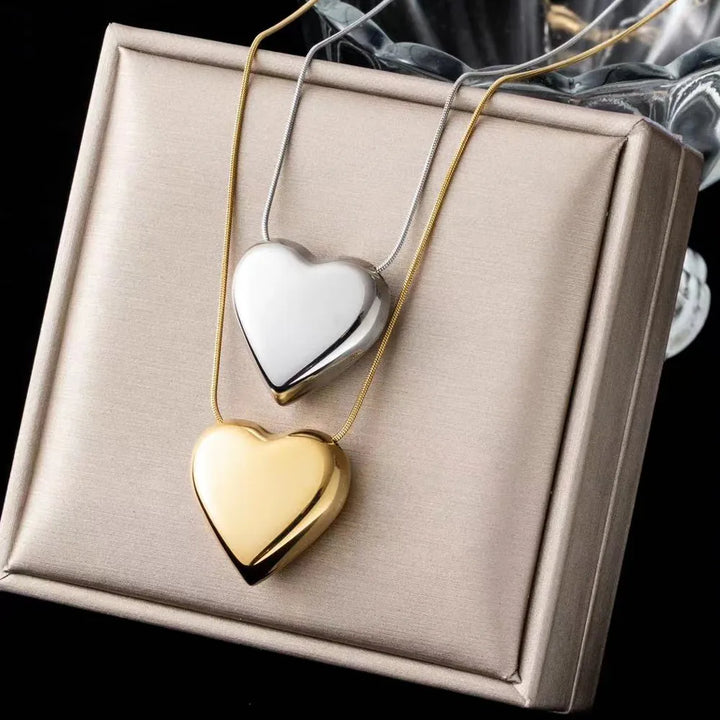 Zwei herzförmige Anhänger, gold und silber, auf Geschenkbox, eleganter Schmuck.