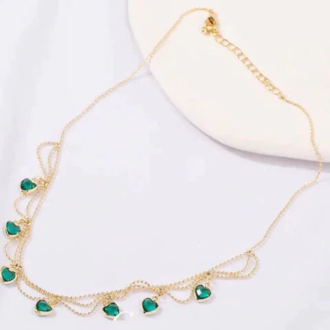 Goldene Halskette mit grünen Herzanhängern, eleganter Schmuck für Damen, modisches Accessoire.