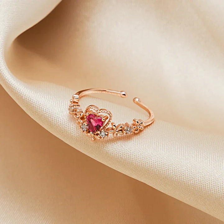 Roségoldener Ring mit Herzform Rubin und Zirkonia, elegant auf beigem Seidenstoff drapiert.