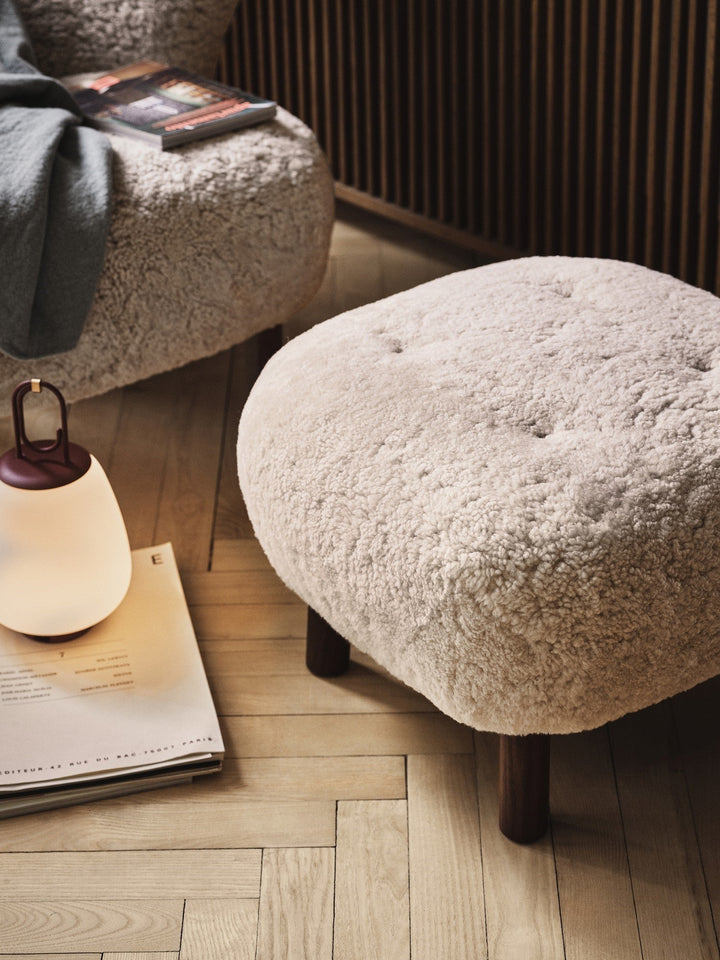 Beiger Schaffell-Hocker auf Holzboden, skandinavisches Design, gemütliche Wohnzimmerdekoration.