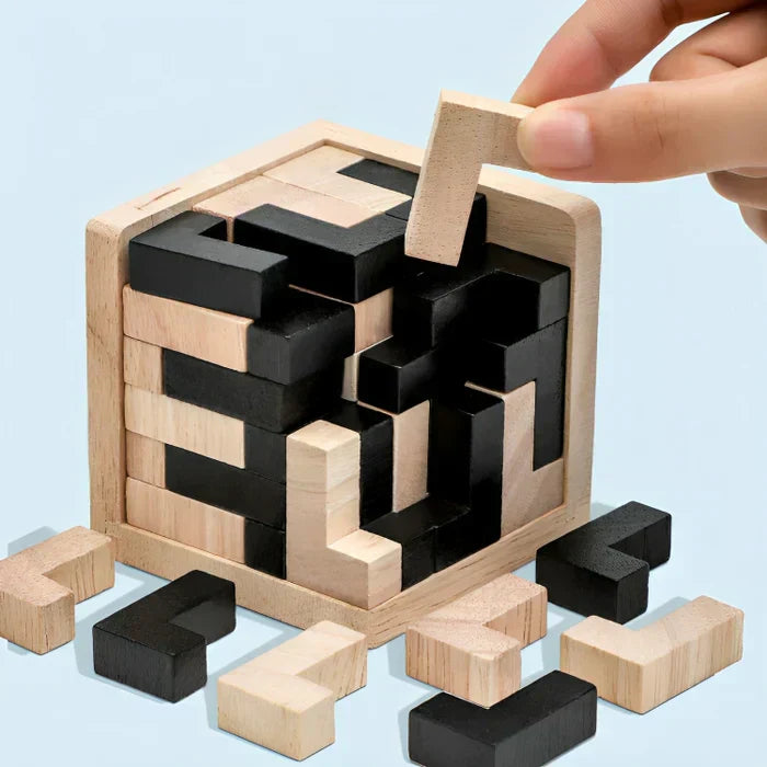 Holzpuzzle in Würfelform, schwarz und natur, Hand fügt Teil hinzu, Denkspiel, Geschicklichkeitsspiel.