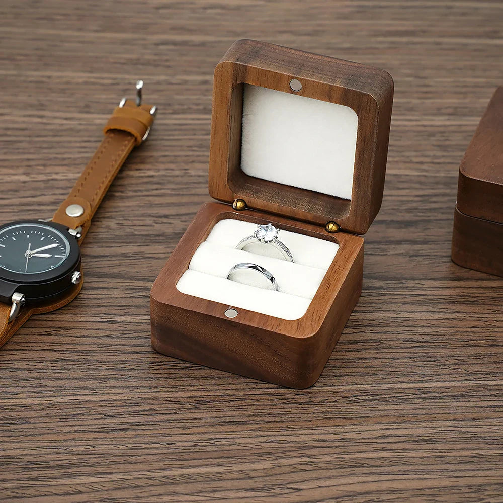Holzringbox mit Verlobungsring und Ehering, Uhr aus Leder, rustikaler Holztisch.