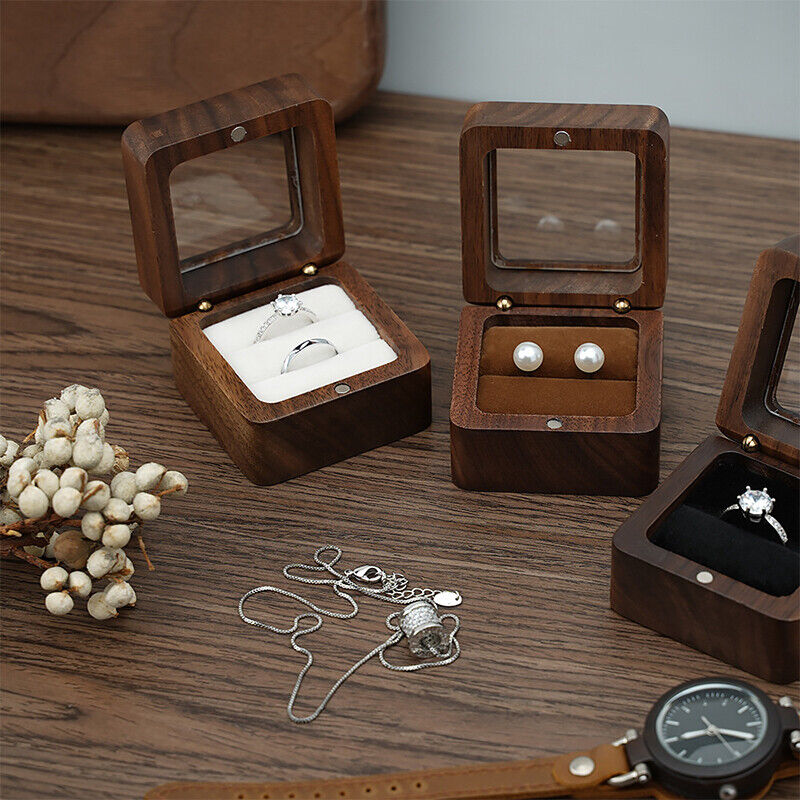 Holzschmuckkästchen mit Ring und Ohrringen, Glasdeckel, auf Holztisch, elegantes Design.