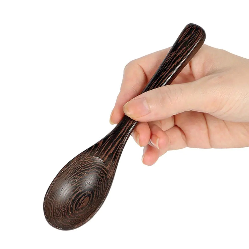 Hand hält dunklen Holzlöffel, ergonomisch, umweltfreundlich, ideal für Küche und Esstisch.