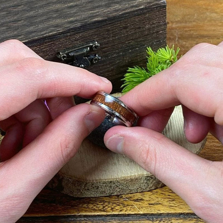 Herrenring aus Holz und Metall, handgefertigt, rustikales Design, Geschenkbox im Hintergrund.