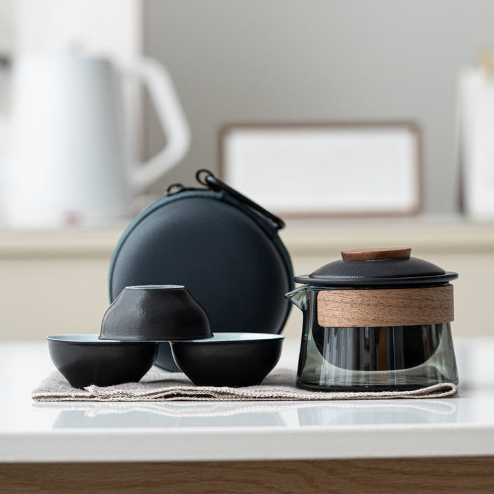 Schwarzes Teeservice mit Glaskanne, Holzgriff und zwei Schalen auf Tisch, modernes Design.