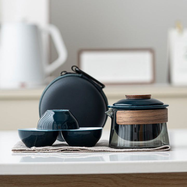 Schwarzes Teeservice aus Glas und Holz mit zwei Tassen und Tragetasche auf Tisch.