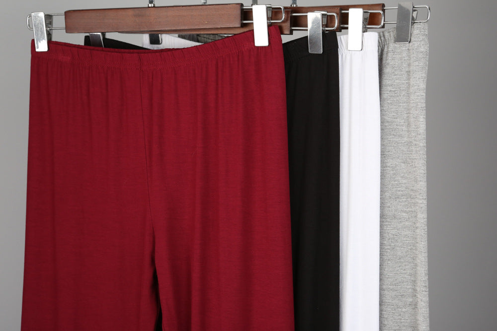 Vier Paar Hosen in Rot, Schwarz, Weiß und Grau auf Kleiderbügeln, Baumwolle, bequem.