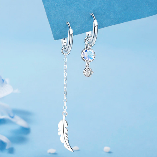 Silberne Ohrringe mit Federanhänger und blauem Kristall, eleganter Schmuck für Damen.