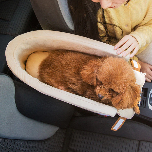 Brauner Pudel im beigen Autositz-Hundebett, bequem und sicher für Reisen.