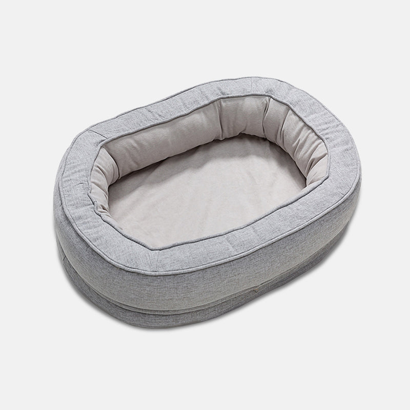 Graues ovales Hundebett aus Stoff, gemütlich und weich, ideal für kleine Hunde.