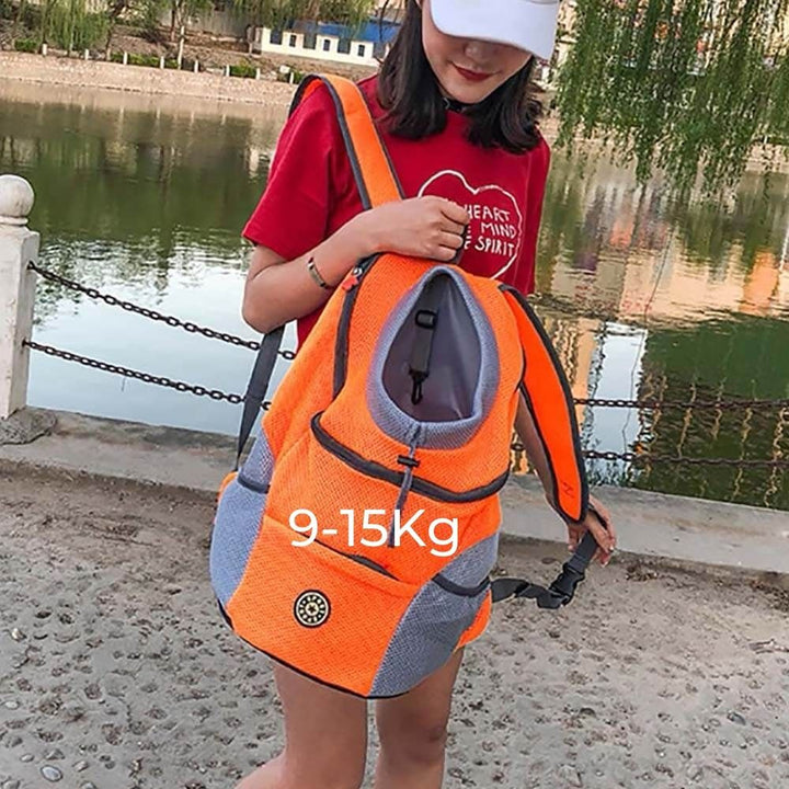 Frau mit orange-grauem Haustier-Rucksack, geeignet für 9-15 kg, am Flussufer.