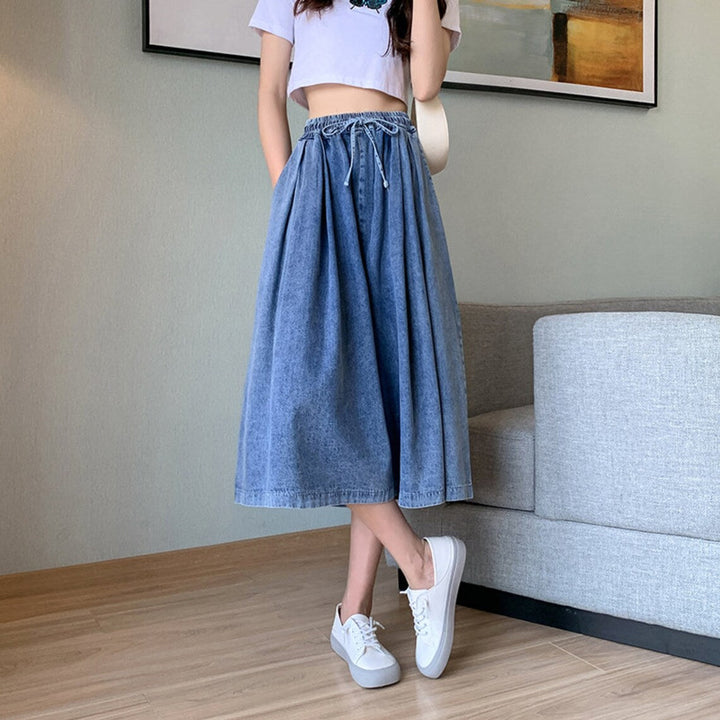 Frau in blauem Jeansrock und weißem T-Shirt, lässiger Stil, modische Freizeitkleidung.