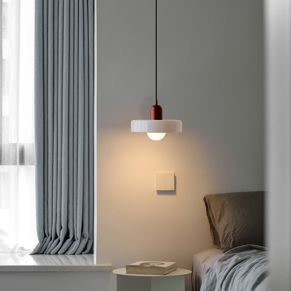 Moderne rote Pendelleuchte über Nachttisch im Schlafzimmer, minimalistisch, skandinavisches Design.