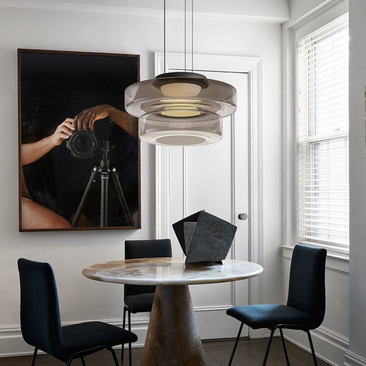 Moderne Hängelampe über rundem Marmortisch in elegantem Esszimmer mit Kunstwerk an der Wand.