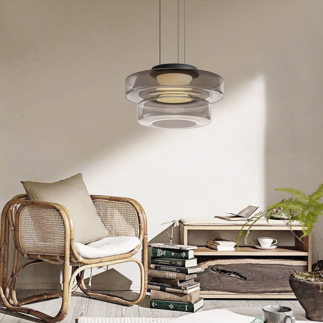 Moderne Glas-Pendelleuchte, transparent, über Rattan-Sessel in stilvollem Wohnzimmer.