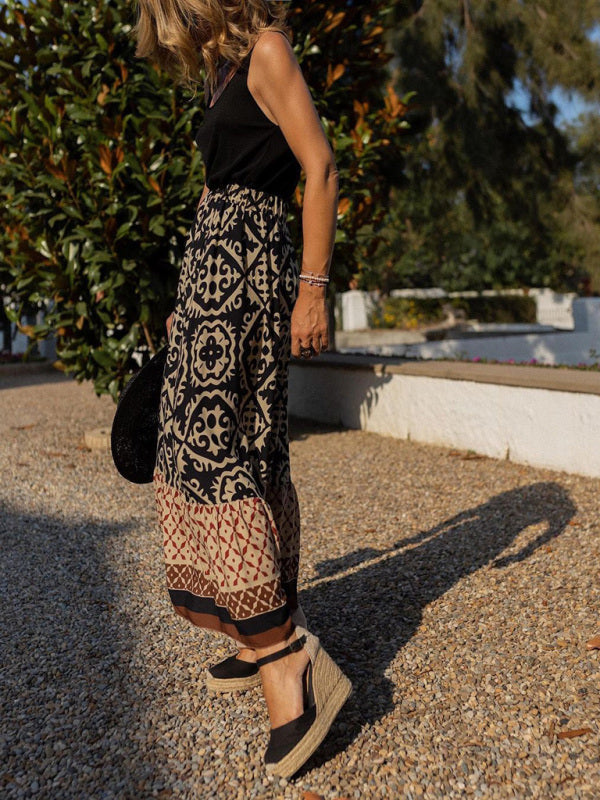 Frau in schwarzem Top und gemustertem Maxirock, trägt schwarze Espadrilles, Sommermode.