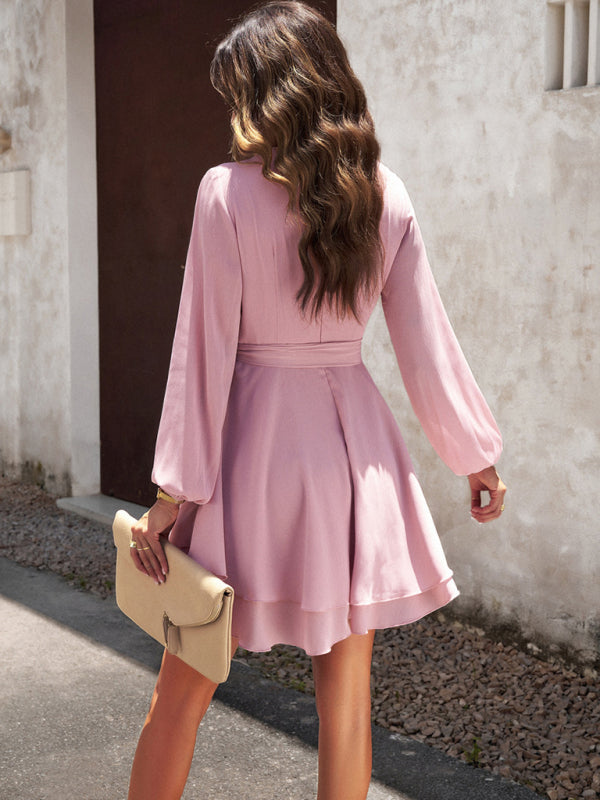 Frau in rosa Kleid mit langen Ärmeln, hält beige Clutch, modisch, elegant, draußen.