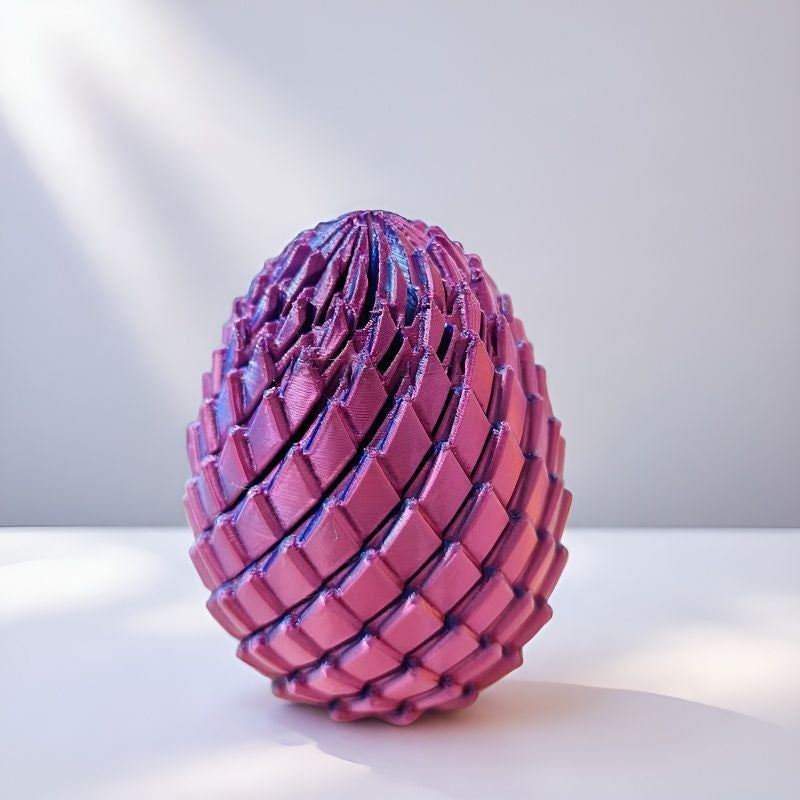 Purpurově růžové vejce s kloubovými šupinami stojí na bílém povrchu ve světle ze strany. 10