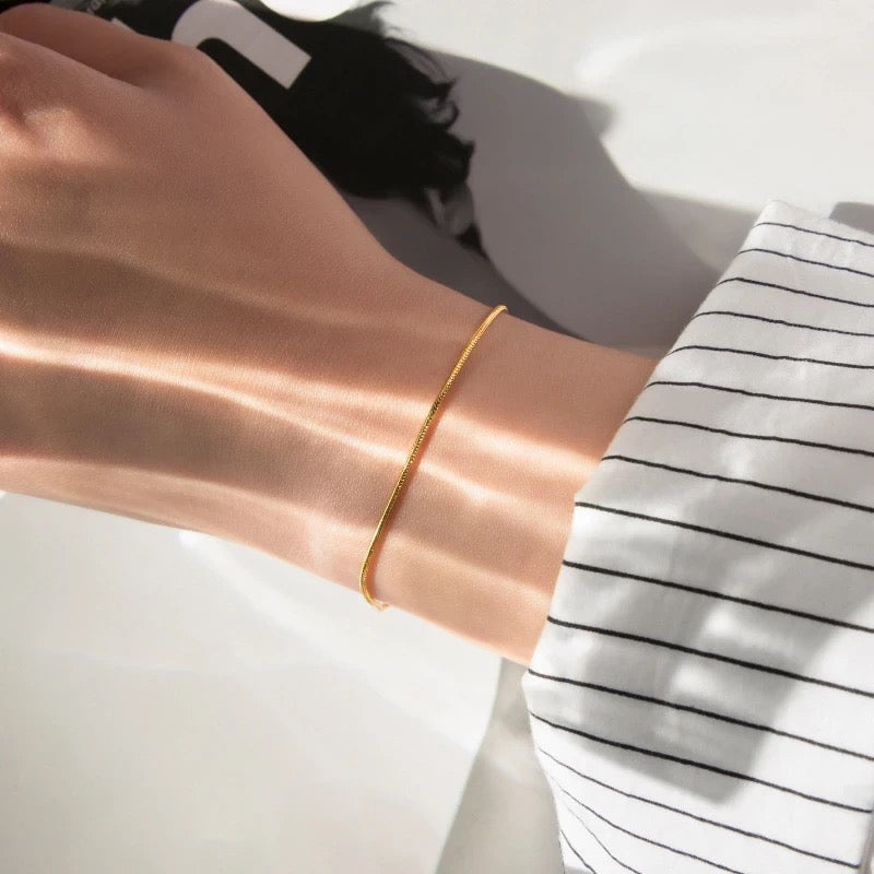 Goldenes Armband am Handgelenk, minimalistisch, elegantes Schmuckdesign, Damenaccessoire.