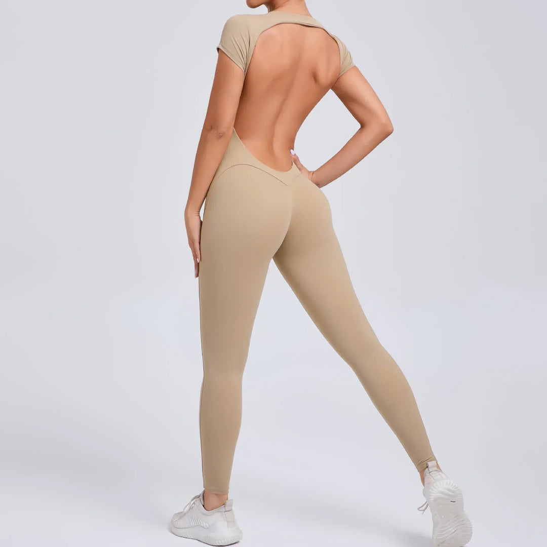 Frau in beige, rückenfreiem Jumpsuit, Ganzkörperansicht, sportlich, modisch, Fitnessbekleidung.
