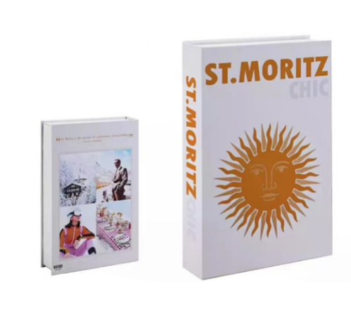Zwei Bücher: "St. Moritz Chic" mit Sonnenmotiv, weißer Einband, und ein kleineres Buch daneben.