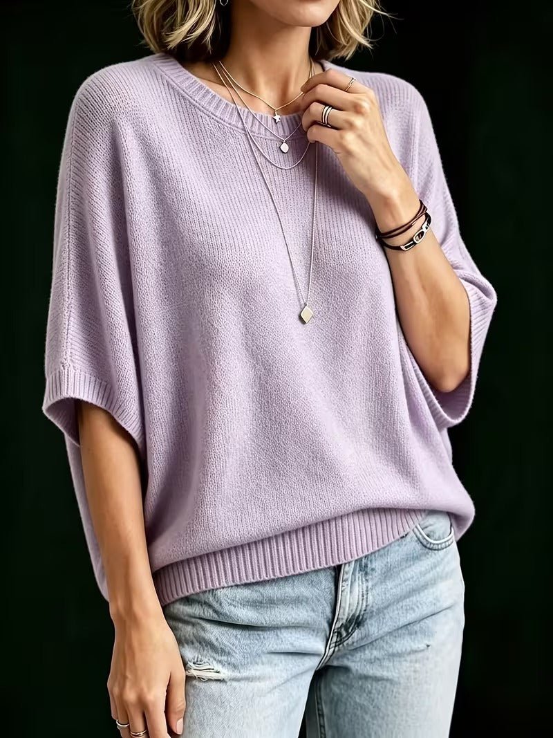 Světle fialový pletený top na modelce, pohled z mírného úhlu, ruka se dotýká náhrdelníku, světlé džíny. 8