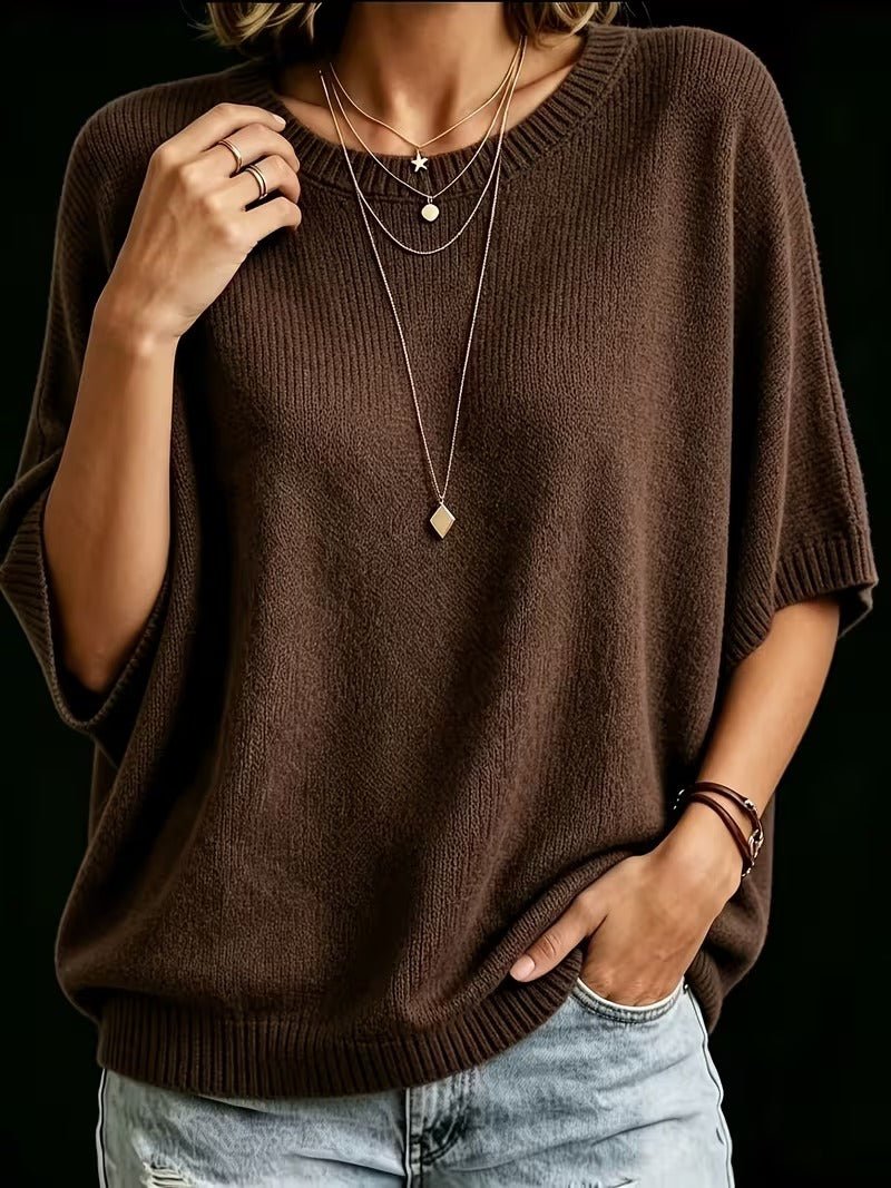 Tmavě hnědý pletený top na modelce, jedna ruka u ramene, druhá v kapse džínů, dlouhý zlatý přívěsek. 20