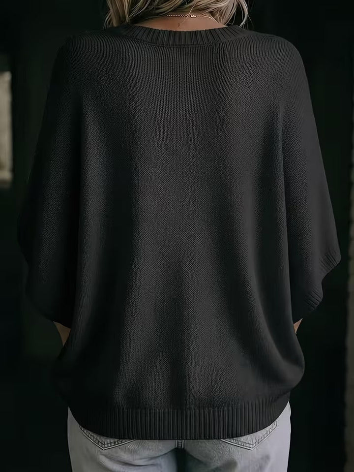 Černý pletený top s netopýřími rukávy, pohled zezadu na modelce ve světlých džínách. 28