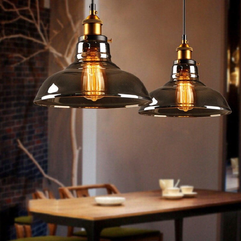 Zwei industrielle Pendelleuchten aus Glas über einem Holztisch in modernem Esszimmer.