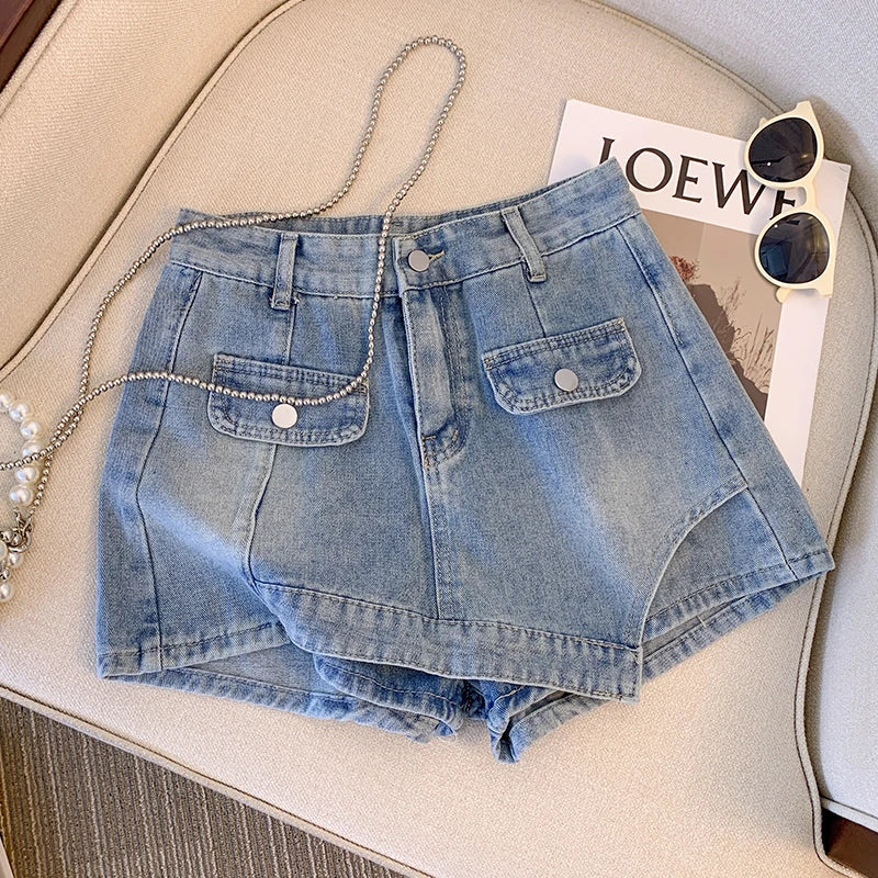 Damen Jeansshorts, hellblau, mit Taschen, auf beigem Sessel, neben Sonnenbrille und Magazin.