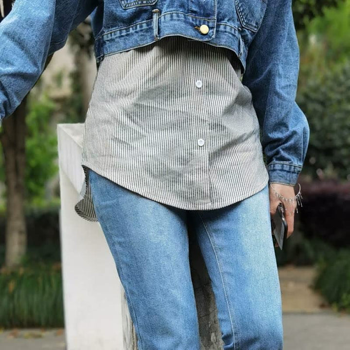 Person in blauer Jeansjacke und Jeans, gestreiftes Hemd, draußen im Park.