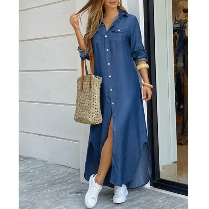 Frau in blauem Jeanskleid mit Knopfleiste, trägt Strohtasche und weiße Sneaker.