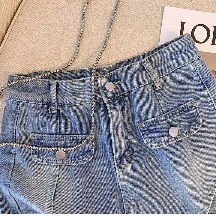 Blaue Jeans mit Taschen und Kettenriemen auf beigem Hintergrund, modisch, lässig.