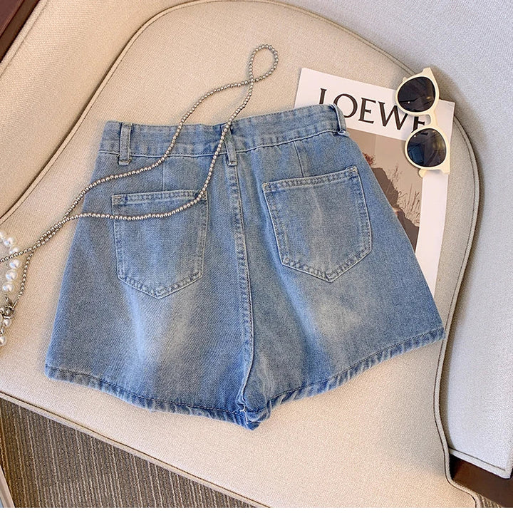 Damen Jeansshorts blau, lässig, Sommermode, Baumwolle, mit Kette, auf Sofa mit Sonnenbrille.