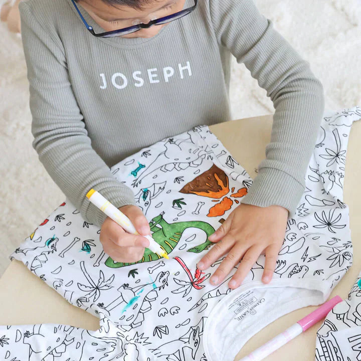 Kind malt Dinosaurier-T-Shirt mit bunten Stiften an, kreatives Spielzeug, Kinderaktivität.