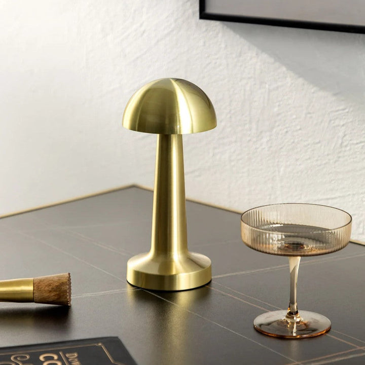 Goldene kabellose LED-Tischlampe, Pilzform, modernes Design, auf Holzoberfläche.