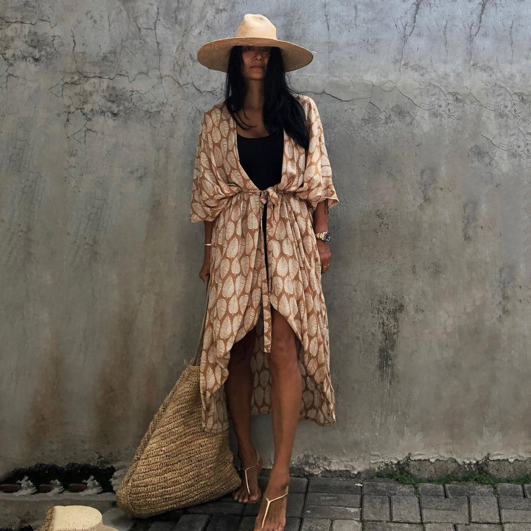 Frau in Sommerkleid mit Strohhut und Tasche vor Betonwand, Boho-Stil, lässige Mode.