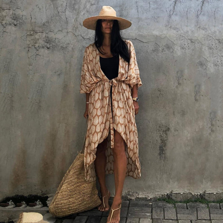 Frau in Sommerkleid mit Strohhut und Tasche vor Betonwand, Boho-Stil, lässige Mode.