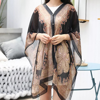 Frau trägt schwarzes, transparentes Kaftan-Kleid mit goldenen Paisley-Mustern, elegant und modisch.