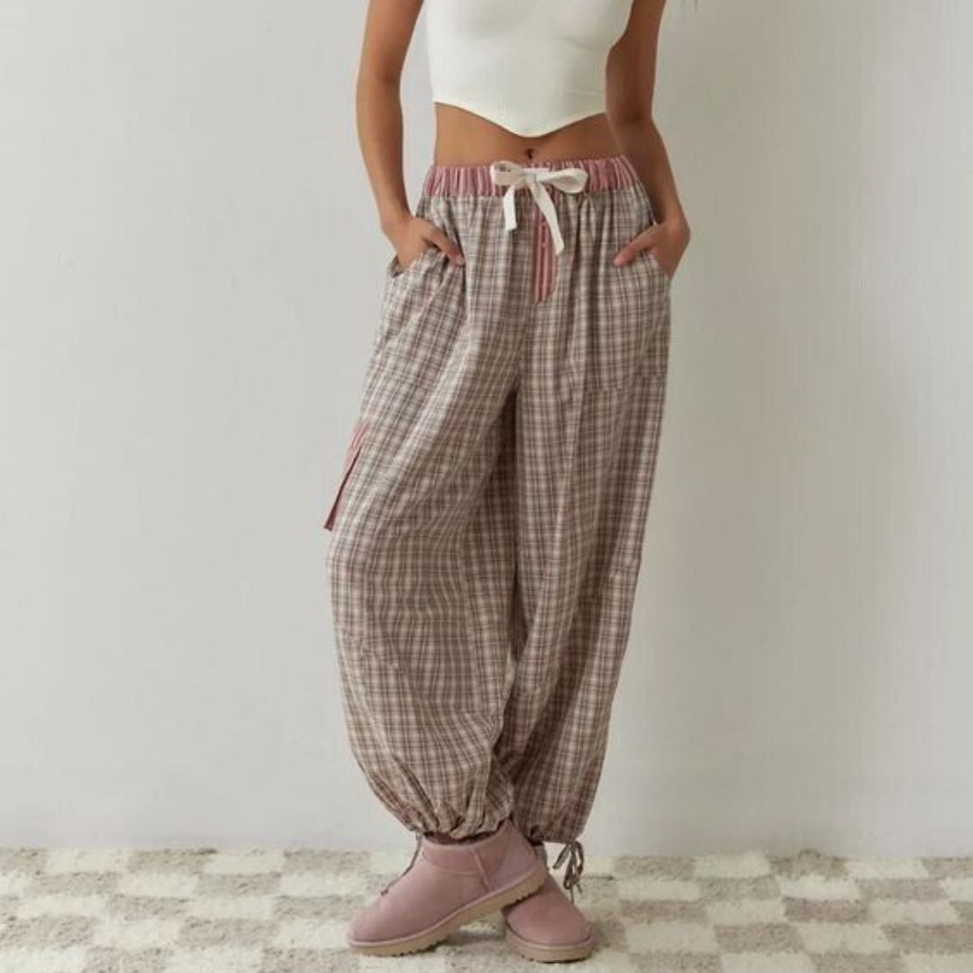 Frau in karierter Jogginghose, weißem Top, rosa Stiefeln; lässige Damenmode, bequem, modern.
