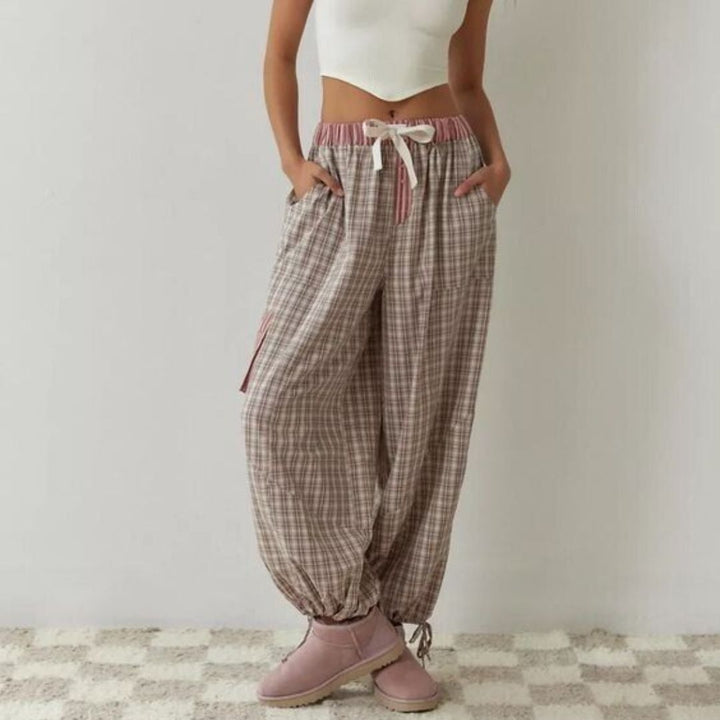 Frau in karierter Jogginghose, weißem Top, rosa Stiefeln; lässige Damenmode, bequem, modern.