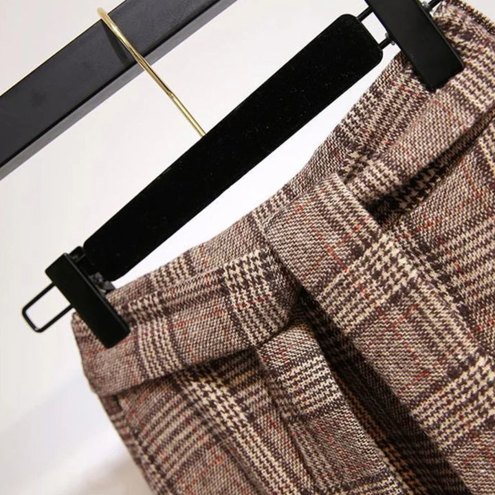Braune karierte Hose aus Wolle, elegant, auf schwarzem Kleiderbügel, Nahaufnahme.