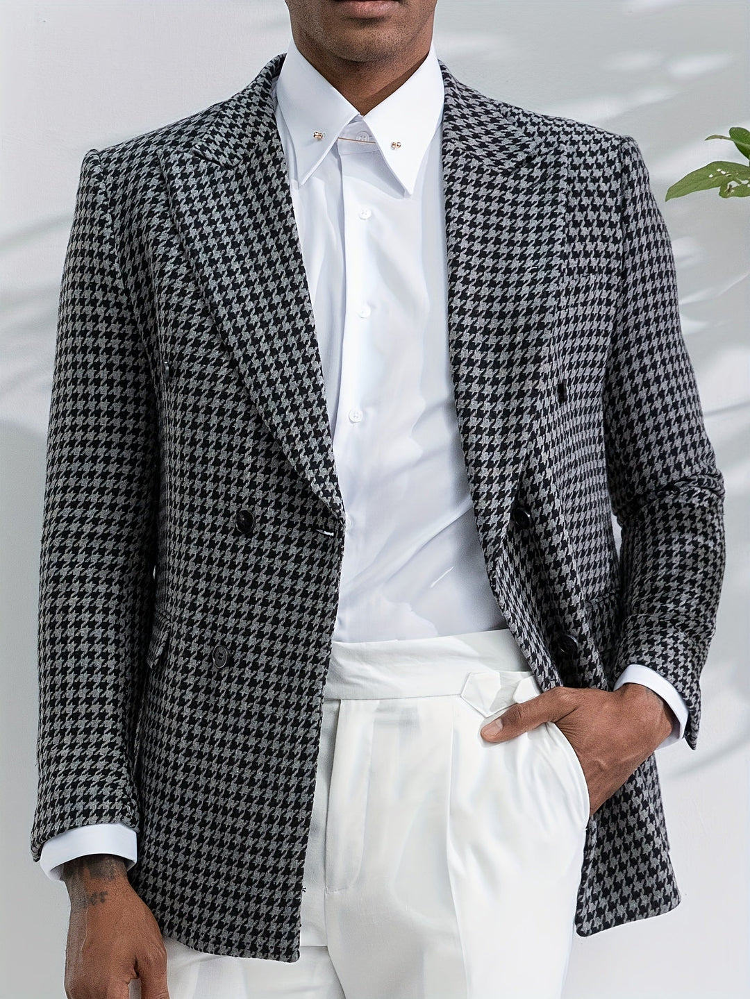 Mann im schwarz-weiß karierten Blazer, weißes Hemd, weiße Hose, stilvolle Herrenmode.