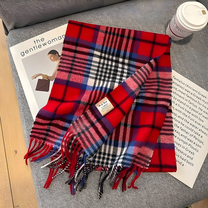 Roter karierten Wollschal auf grauem Sofa mit Zeitschrift und Kaffeebecher.