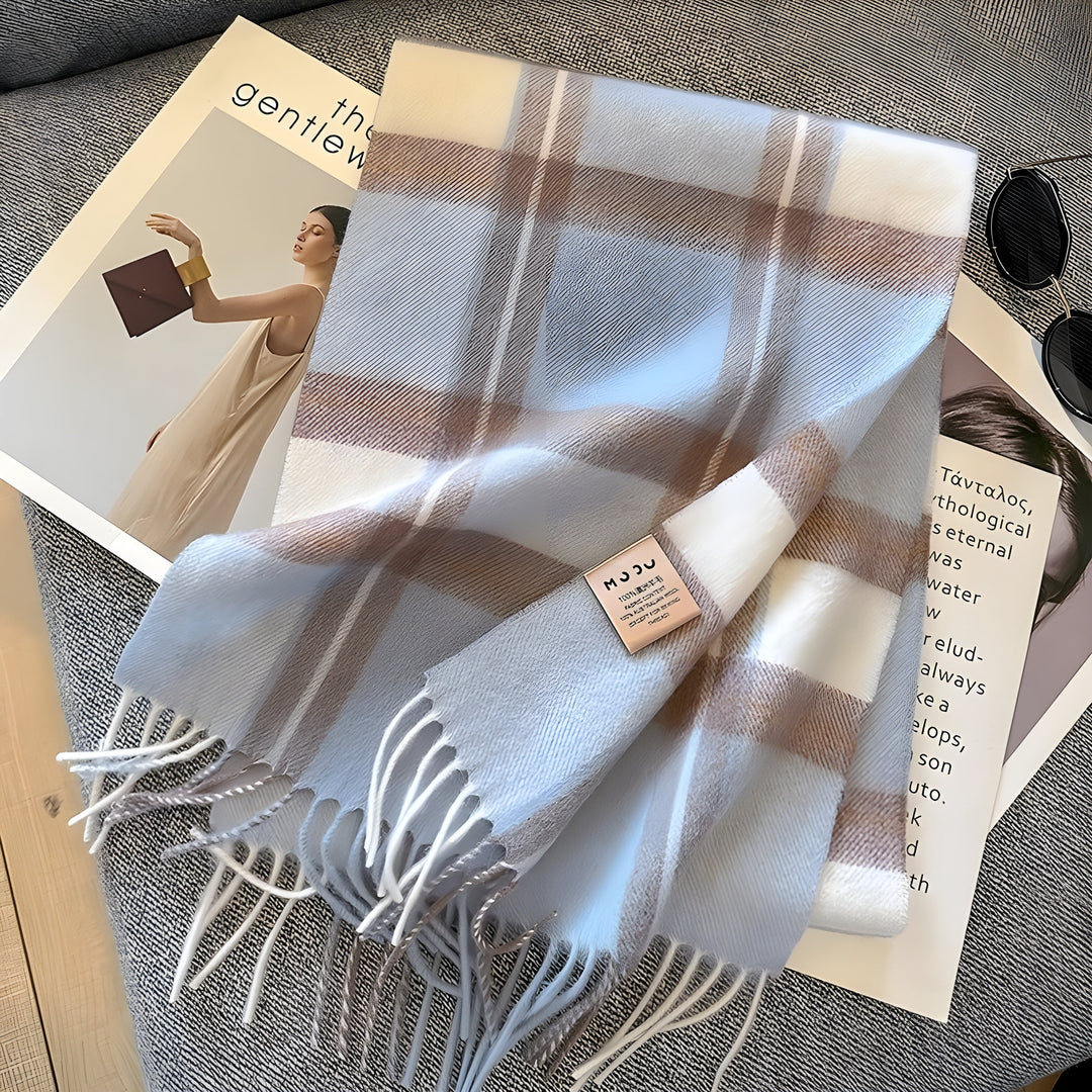 Kariertes Kaschmirschal in Weiß und Beige auf grauem Sofa, modisches Accessoire.