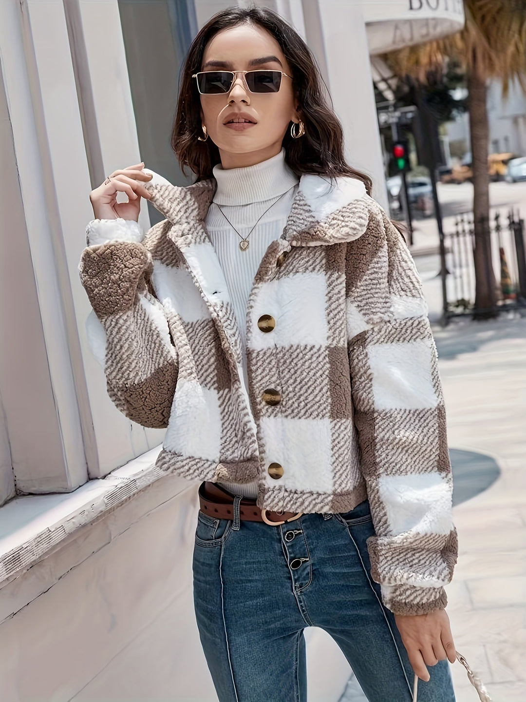 Frau in kariertem Teddyjacke, braun-weiß, mit Sonnenbrille, modisch, Herbstmode, draußen.