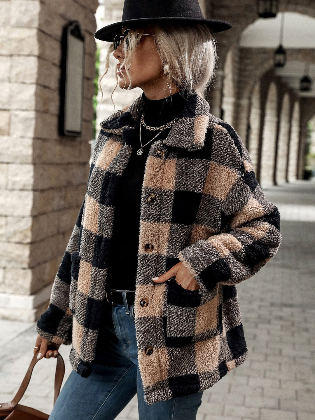 Frau in kariertem Wollmantel, schwarz-beige, Herbstmode, stilvoll, draußen, mit Hut.